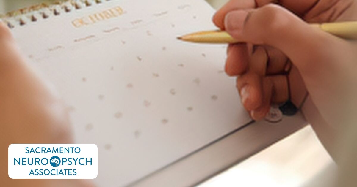 Hand with a pen over a monthly planner page